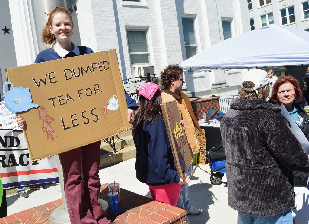 Hannah Abner holds up a sign at the No Kings rally that harkens back to the Boston Tea Party. She said she is unhappy about many issues but especially the immigration enforcement actions of ICE.