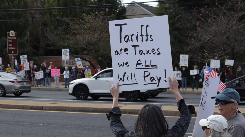 Protester with sign opposing tariffs.